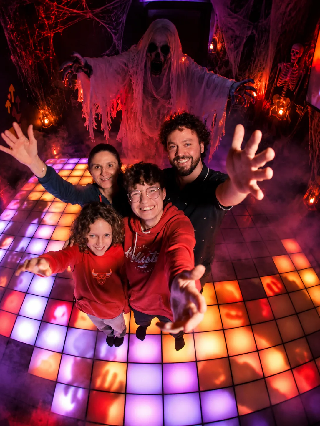 Famille souriante sur les dalles interactives dans une ambiance Halloween